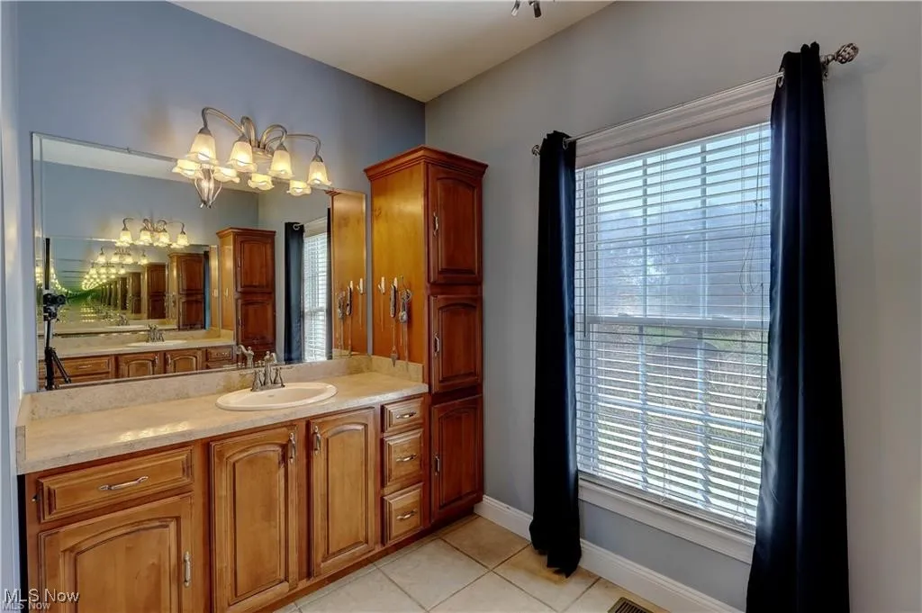 Bathroom featuring vanity, light tile patterned flooring, and a chandelier