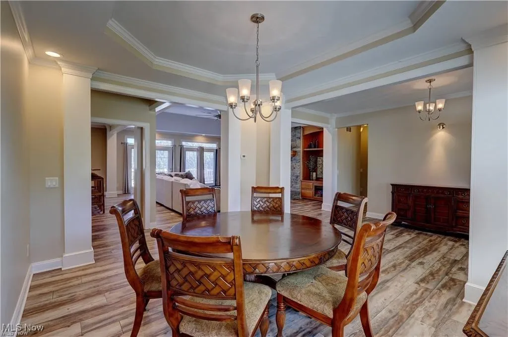 Dining room featuring a chandelier, crown molding, light wood-style flooring, and a tray ceiling