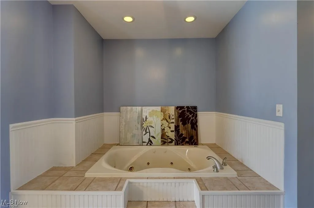 Full bathroom with a tub with jets, recessed lighting, and a wainscoted wall