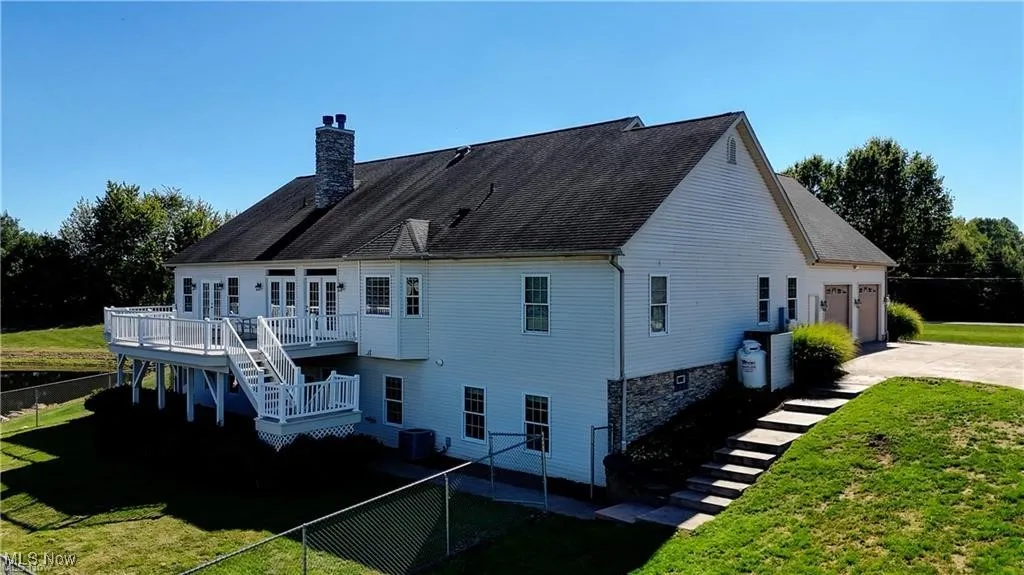 Back of house featuring stairs, a fenced backyard, a chimney, a deck, and a patio