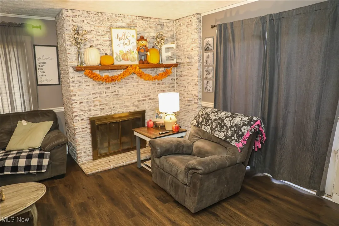 Sitting room featuring crown molding, a brick fireplace, and dark wood-type flooring