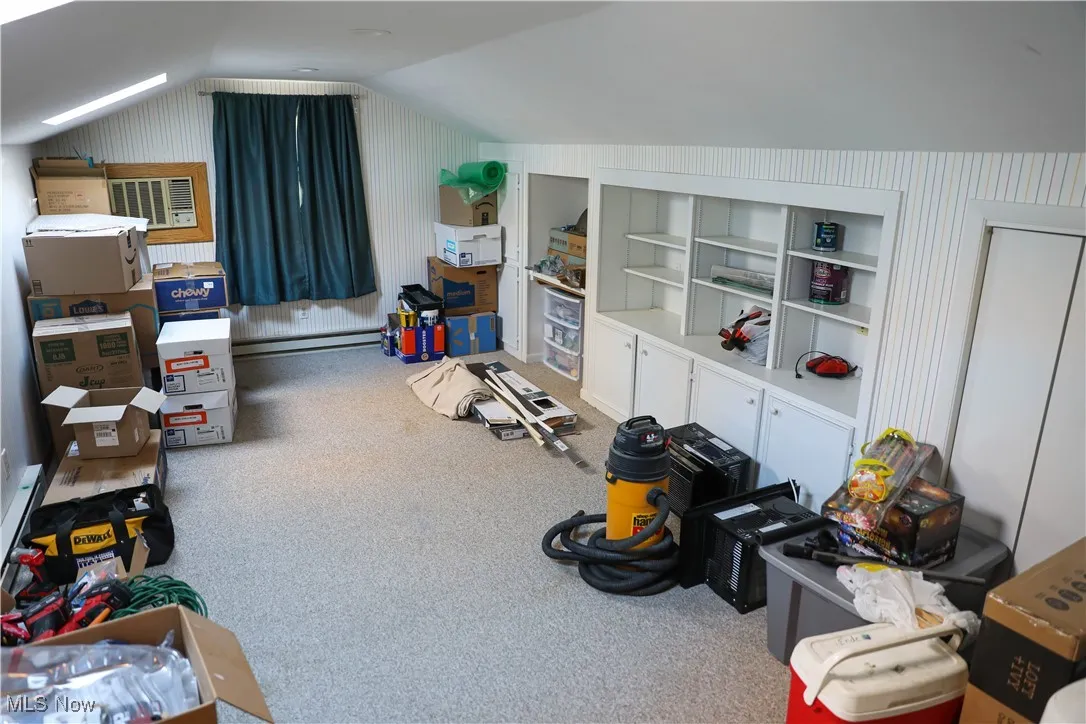 Bonus room featuring vaulted ceiling, a skylight, a baseboard heating unit, and light carpet
