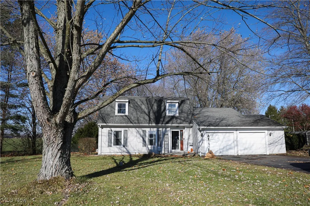Colonial inspired home with a front lawn, asphalt driveway, an attached garage, and roof with shingles