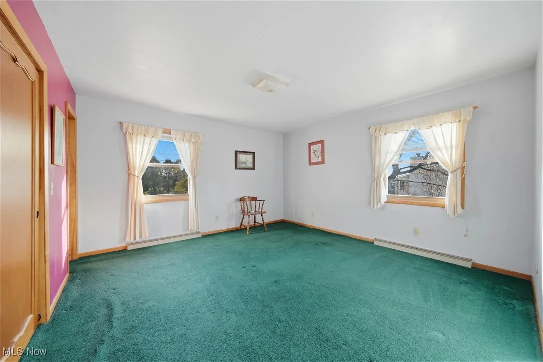 Carpeted spare room with baseboard heating, healthy amount of natural light, and a baseboard heating unit
