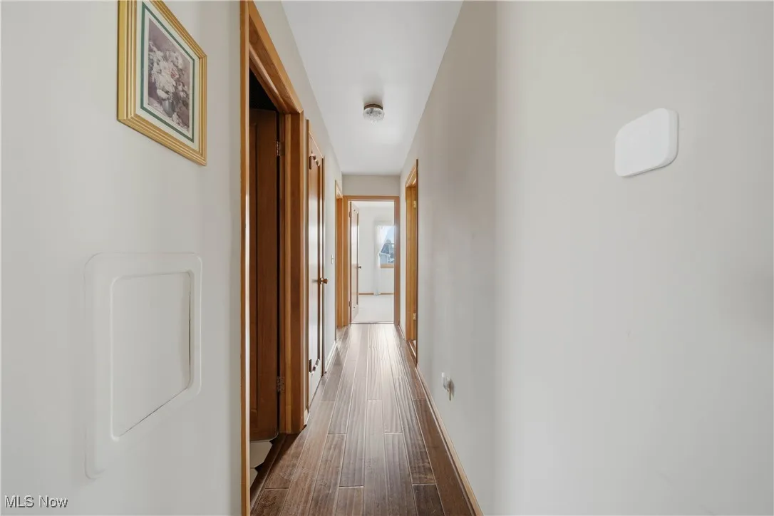 Hall with dark wood-type flooring and baseboards