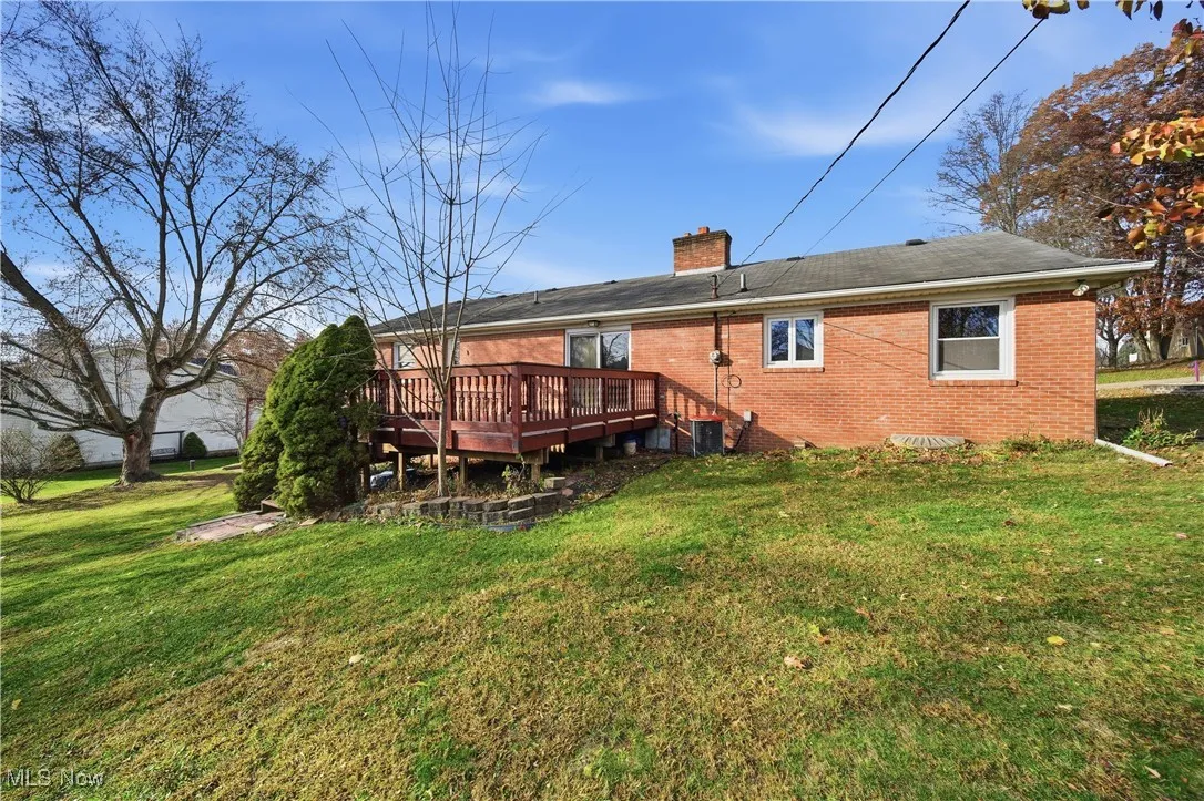 Rear view of house with a yard, a deck, and a chimney