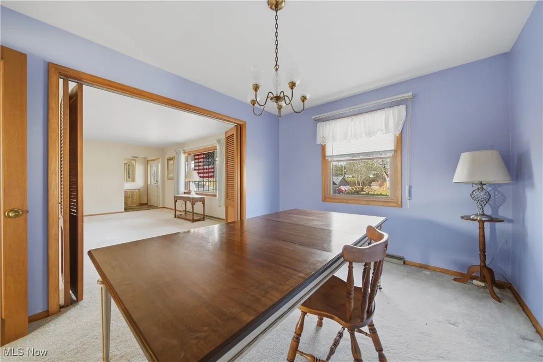 Dining space featuring light carpet and a chandelier