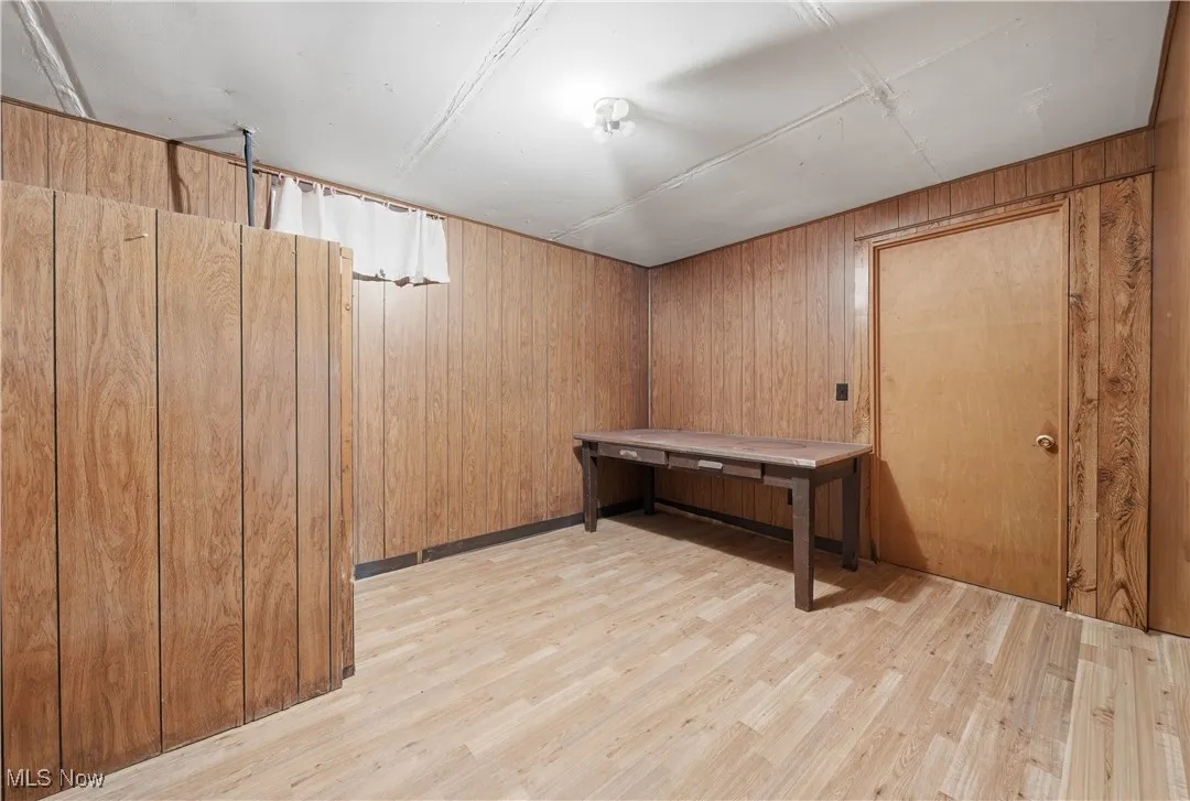 Finished basement featuring light wood-style floors and wood walls