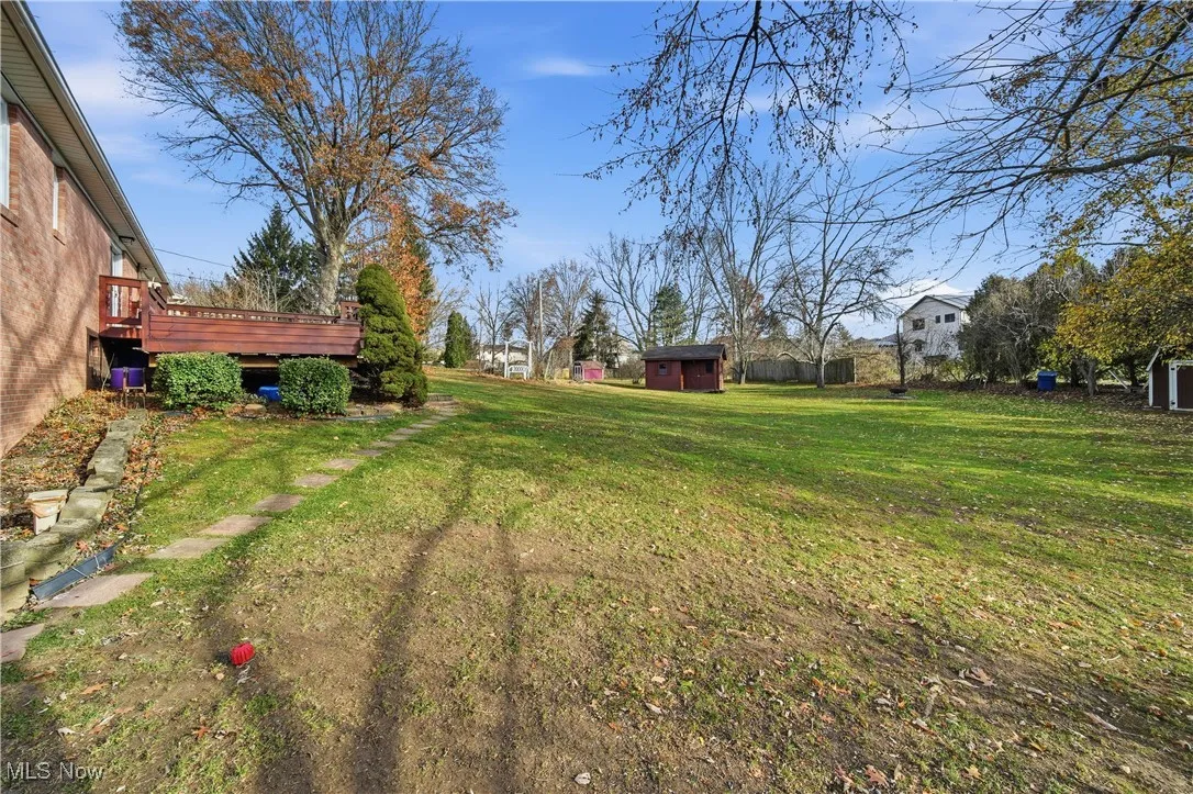 View of grassy yard featuring a shed and a deck