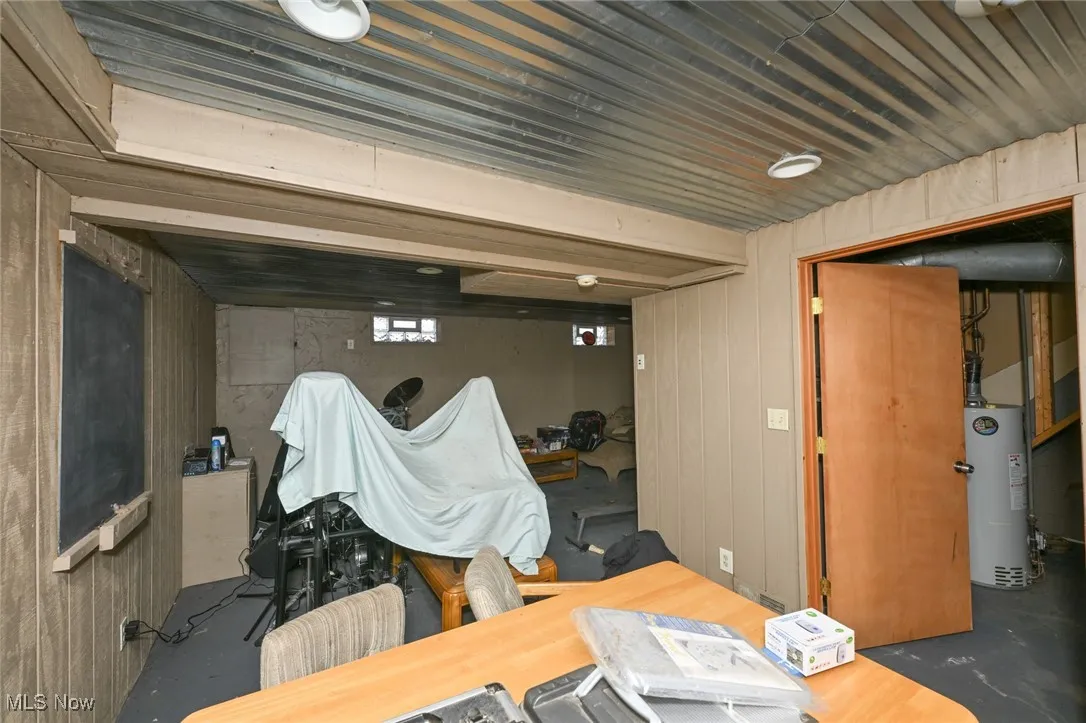 Unfinished basement featuring wood walls and water heater