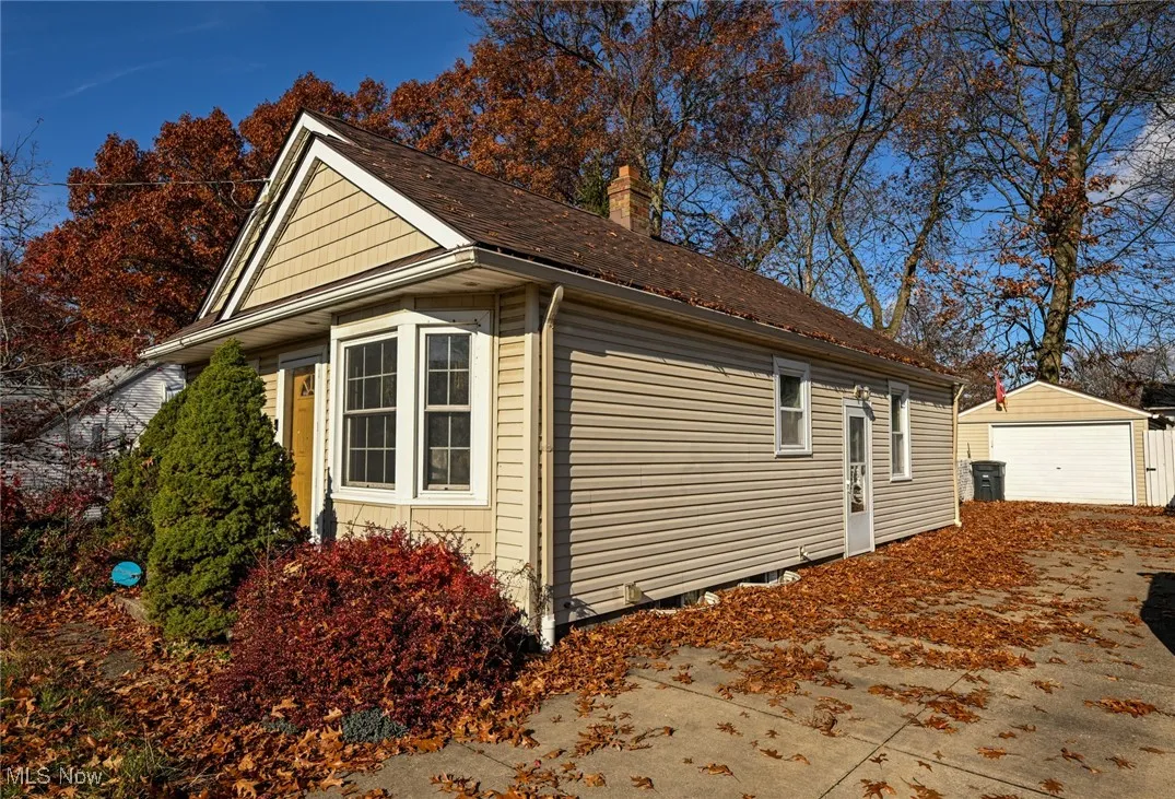 View of property exterior featuring an outdoor structure, a garage, and a chimney
