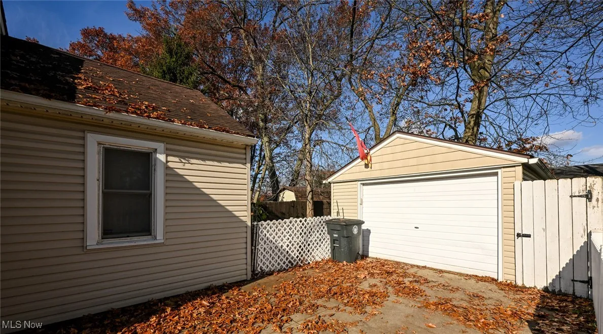 View of side of property featuring an outdoor structure, a detached garage, and a gate