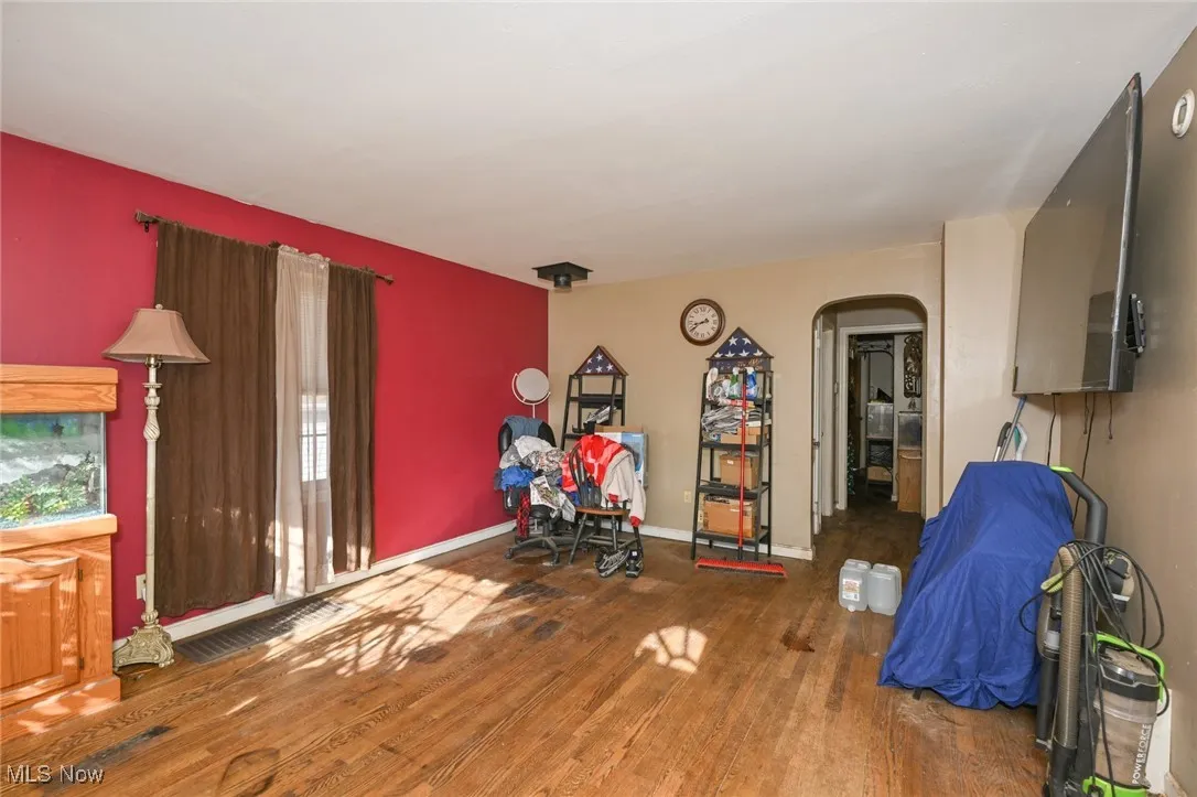 Playroom with arched walkways and dark wood-type flooring