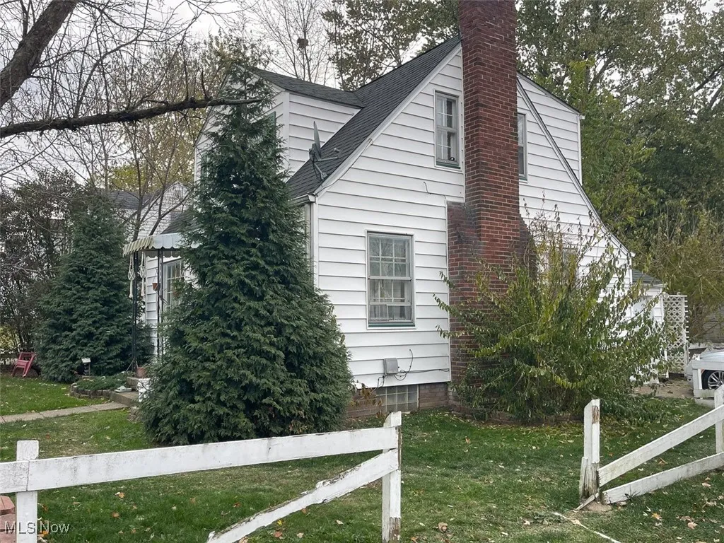 View of side of home with a chimney and roof with shingles