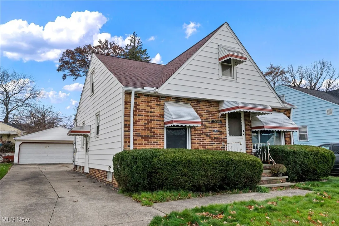 View of front of property featuring roof with shingles, and a detached garage