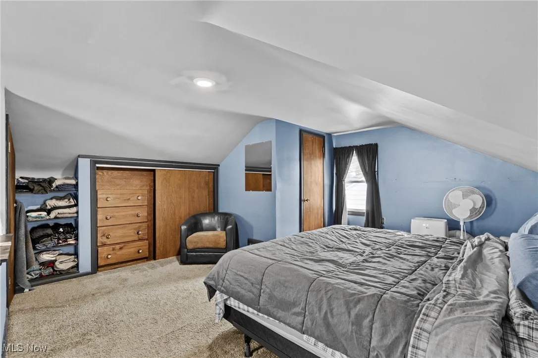 Carpeted primary bedroom featuring built ins and lofted ceiling