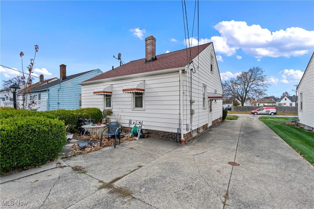Rear view of house featuring a chimney and driveway
