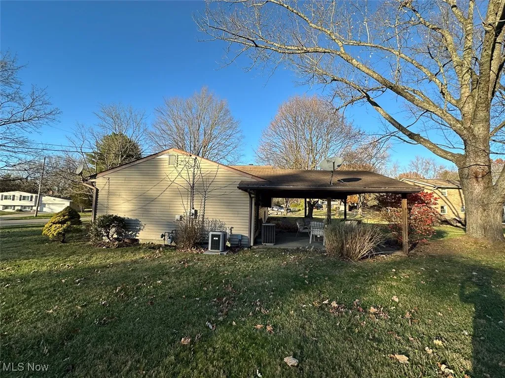 View of side of property featuring a patio and a lawn