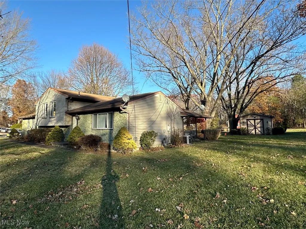 View of side of home with a storage shed, a yard, and stone​​‌​​​​‌​​‌‌​‌‌​​​‌‌​‌​‌​‌​​​‌​​ siding