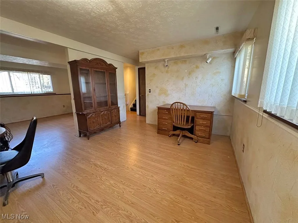 Living room area featuring light wood finished floors and a textured ceiling