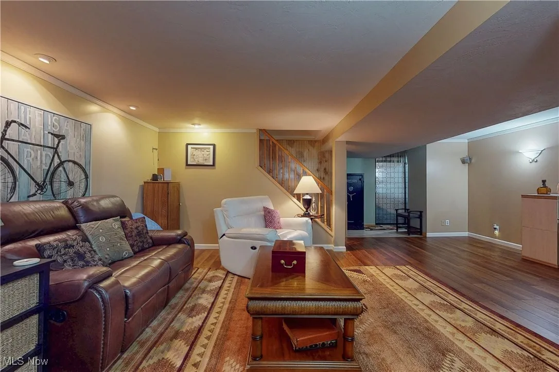 Living room featuring crown molding, stairs, and wood finished floors