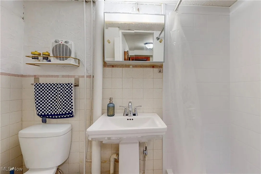Full bathroom featuring tile walls and a shower with shower curtain