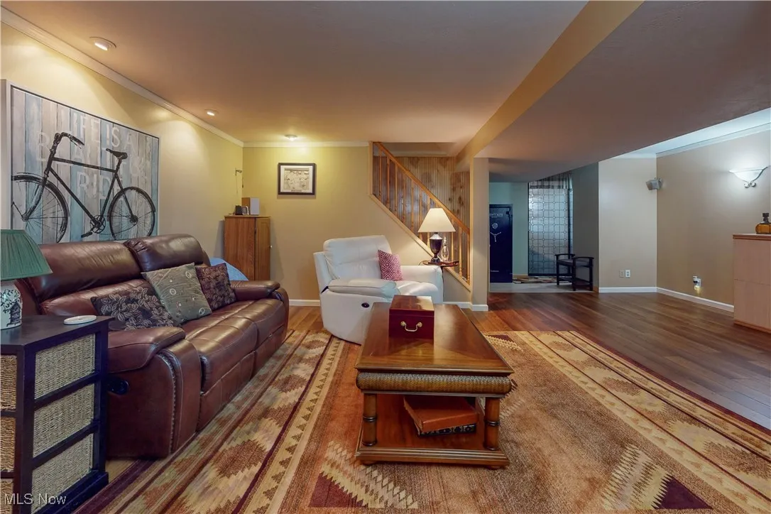 Living room with crown molding, wood finished floors, and stairway