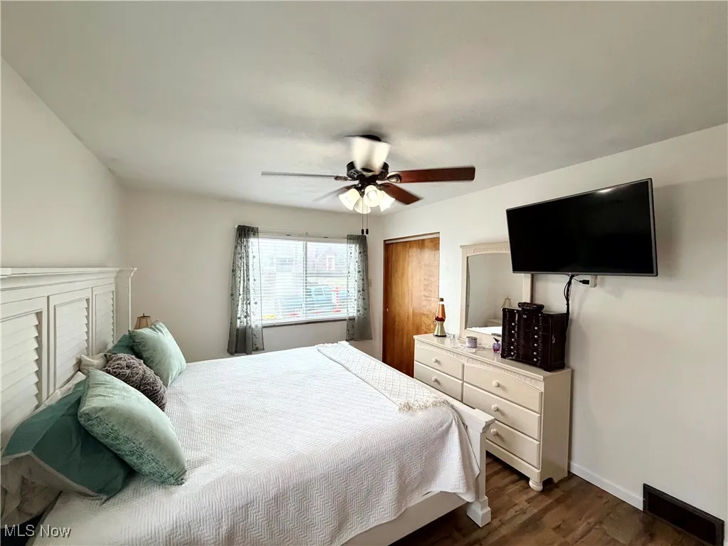 Bedroom with dark wood-style flooring, ceiling fan, and a closet