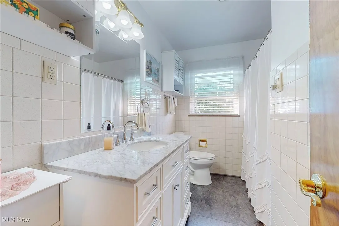 Bathroom with vanity, tile walls, light tile patterned flooring, and curtained shower