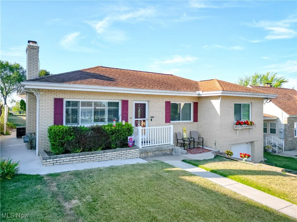 View of front of home featuring a front lawn, a chimney, roof with shingles, and brick siding
