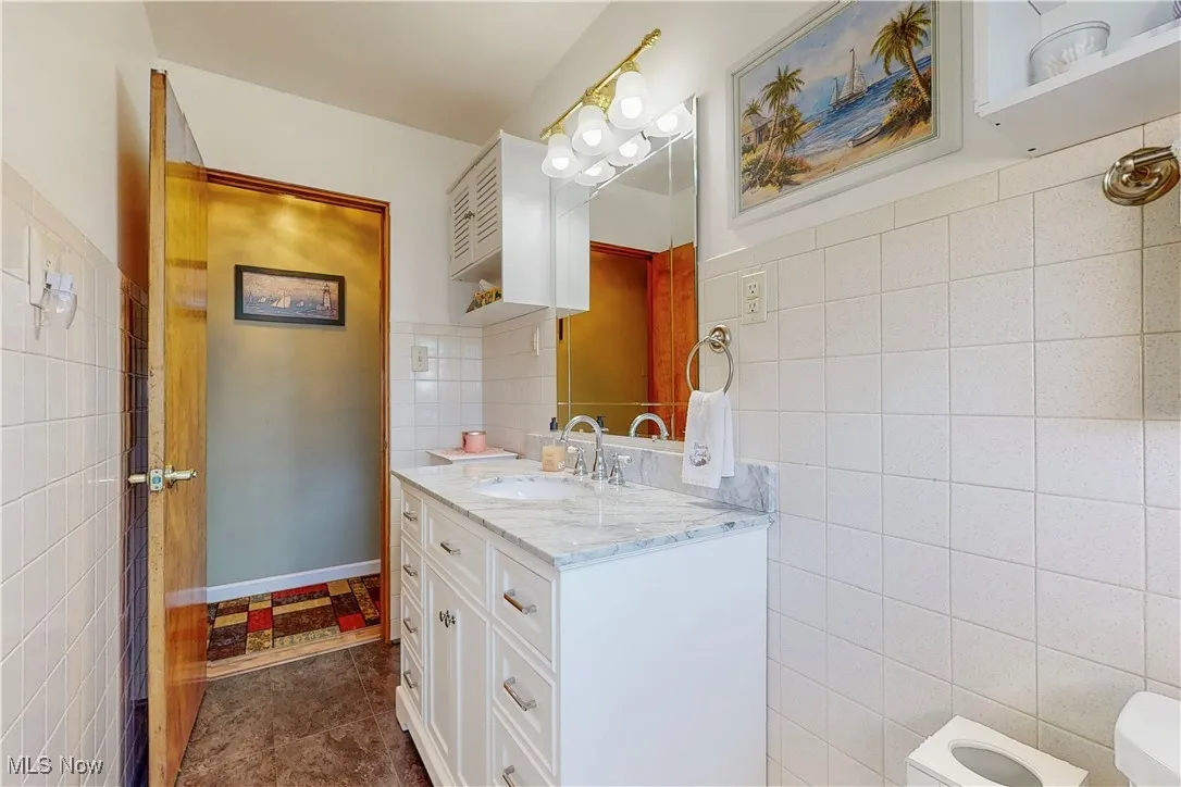 Bathroom featuring vanity, tile walls, and dark tile patterned flooring