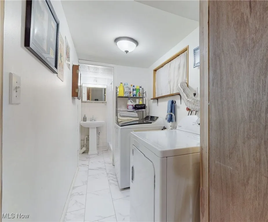 Laundry area featuring light marble finish flooring and washing machine and dryer