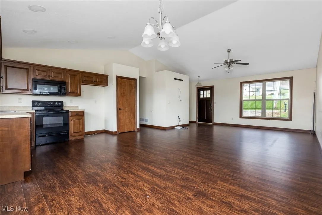 Kitchen featuring black appliances, light countertops, a chandelier, vaulted ceiling, and hanging light fixtures