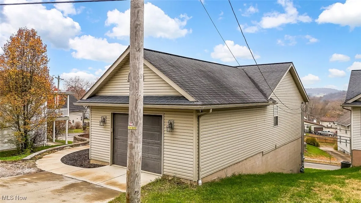View of home's exterior with roof with shingles and a garage