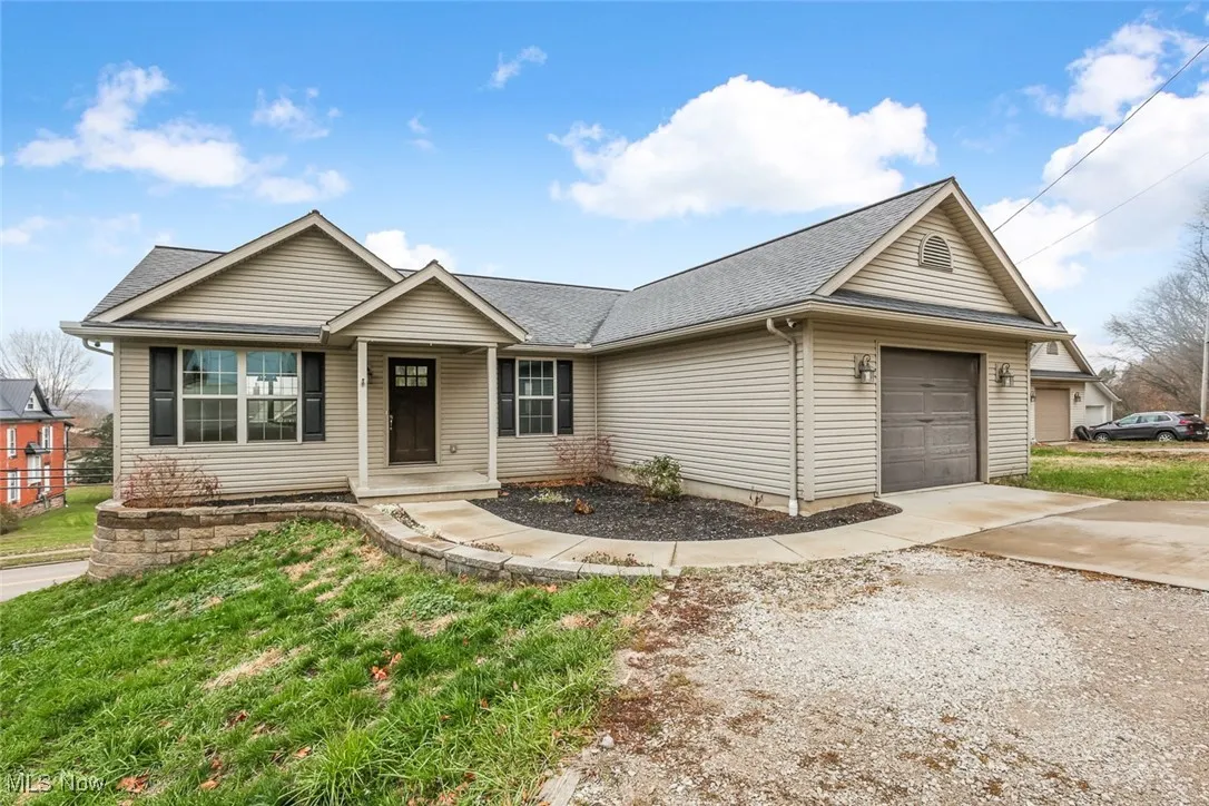 Ranch-style house featuring an attached garage, a shingled roof, a porch, and driveway