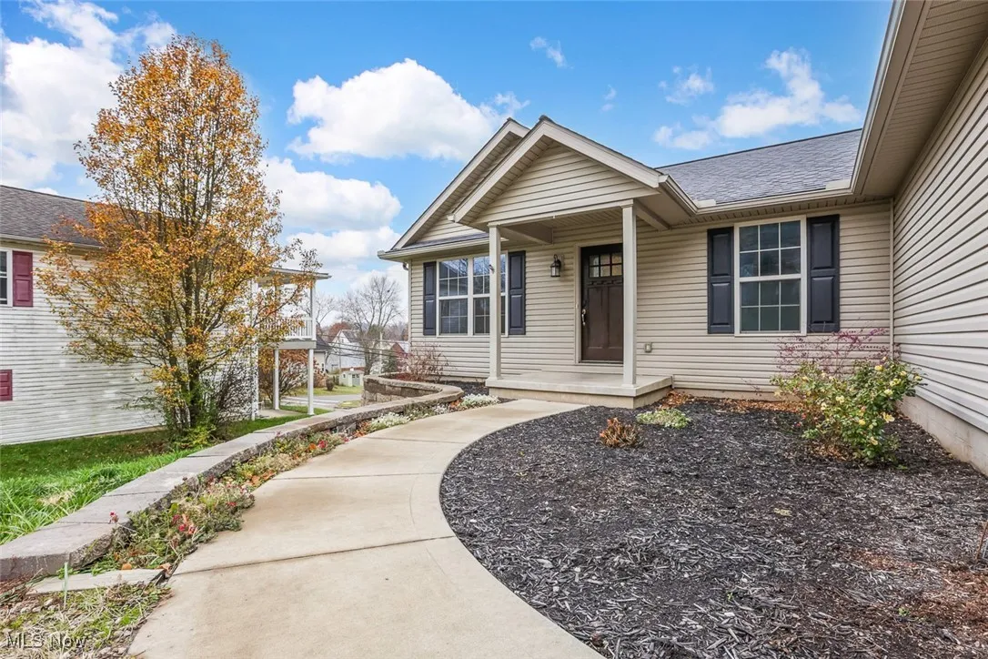 Property entrance with covered porch and a shingled roof