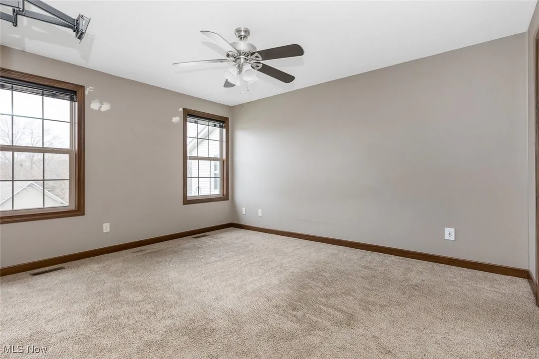Carpeted empty room featuring baseboards and a ceiling fan