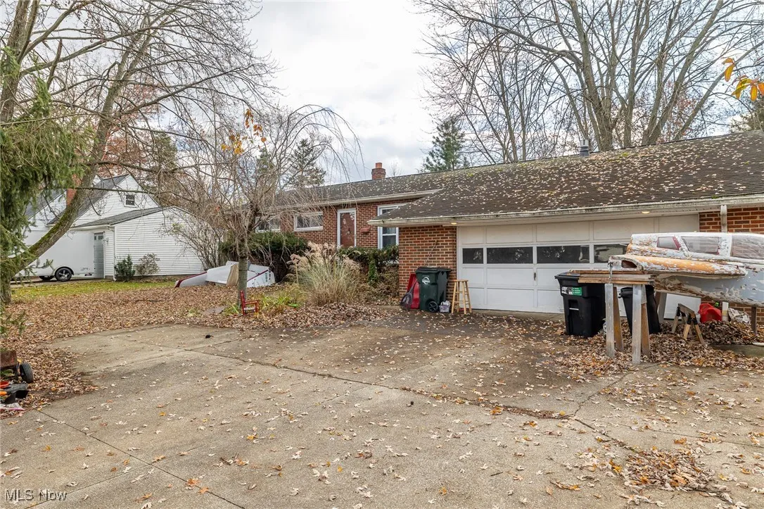 Ranch-style house with driveway, a chimney, brick siding, and an attached garage