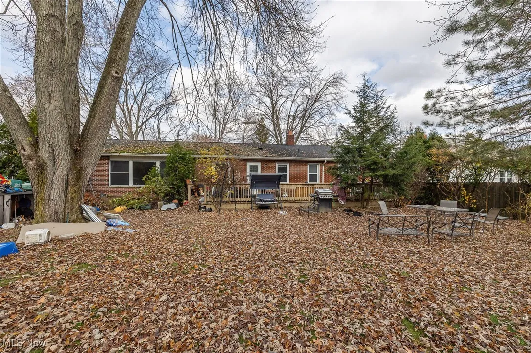 Rear view of property featuring brick siding, a wooden deck, and a chimney