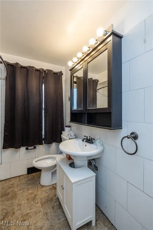 Full bathroom with backsplash, vanity, tile walls, and stone tile flooring