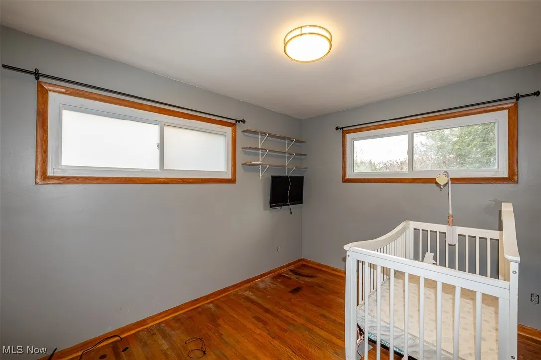 Bedroom featuring hardwood / wood-style flooring, multiple windows, and a crib