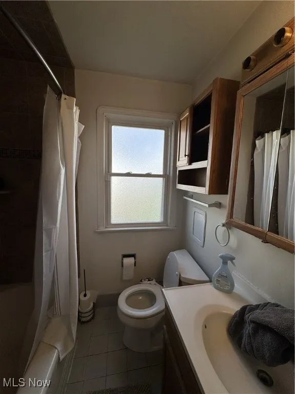Full bathroom featuring tile patterned floors, shower / bath combination with curtain, and vanity