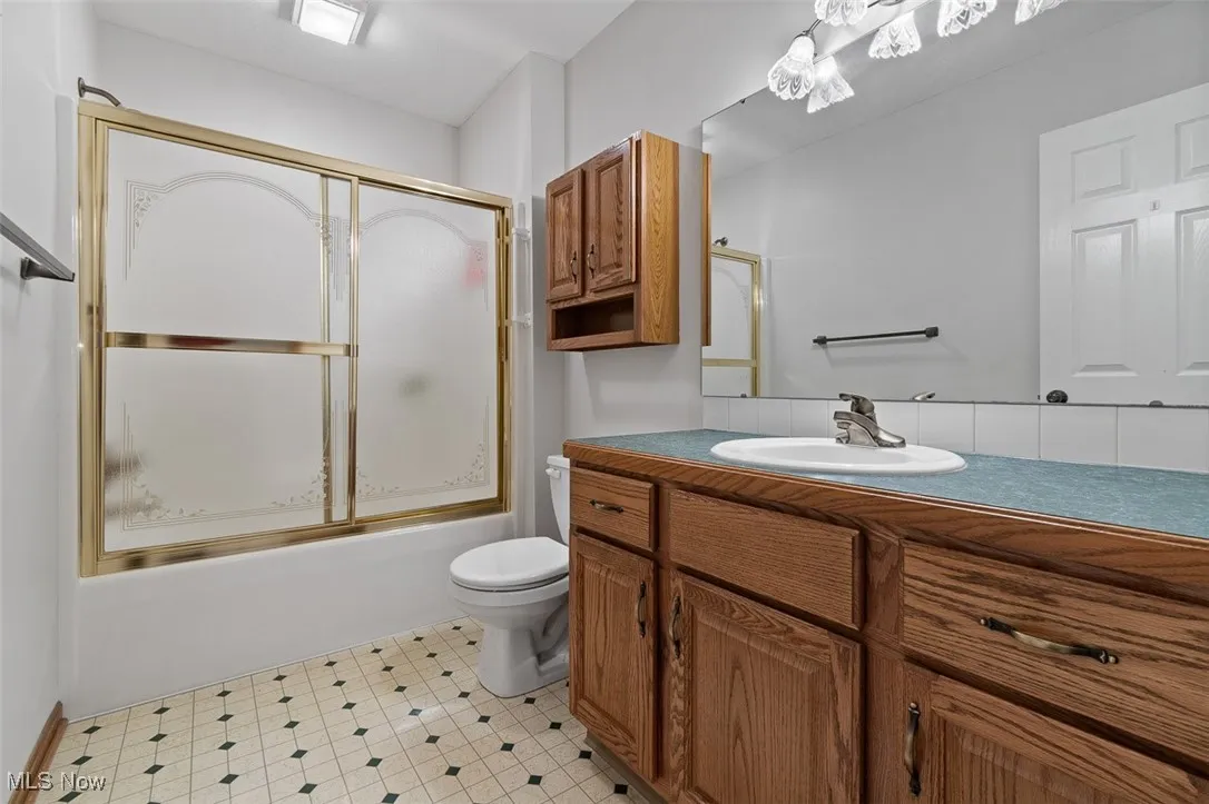 Bathroom featuring vanity and shower / bath combination with glass door