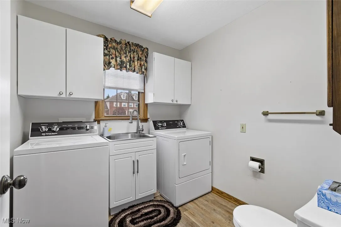 Washroom with independent washer and dryer and light wood-type flooring
