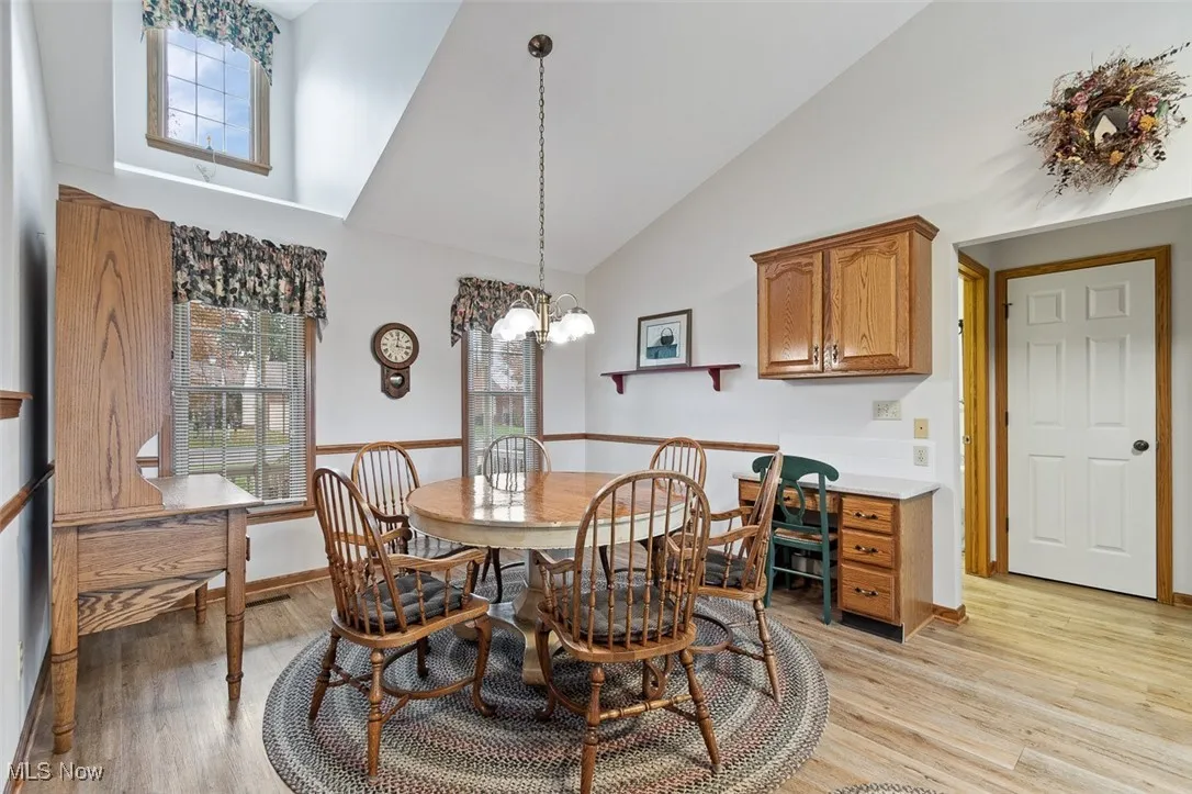 Dining space featuring light wood finished floors, a chandelier, and high vaulted ceiling