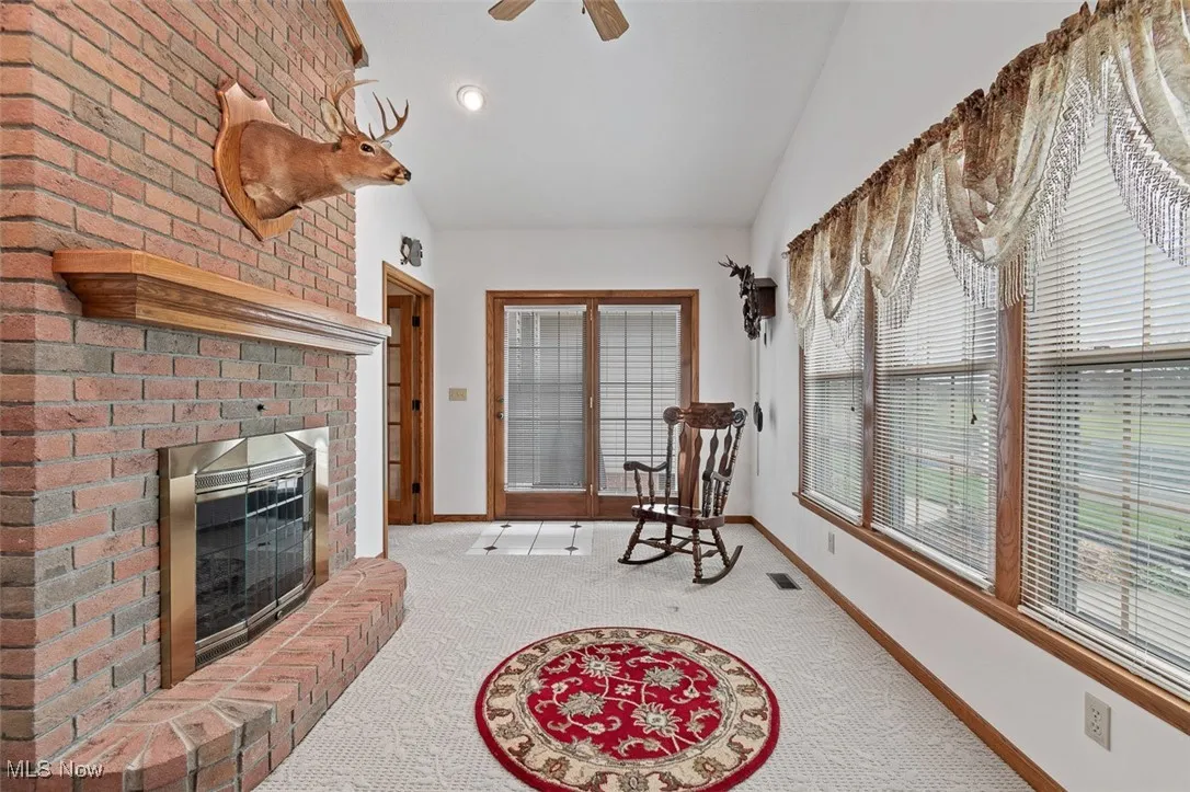 Sitting room featuring carpet floors, a brick fireplace, and ceiling fan