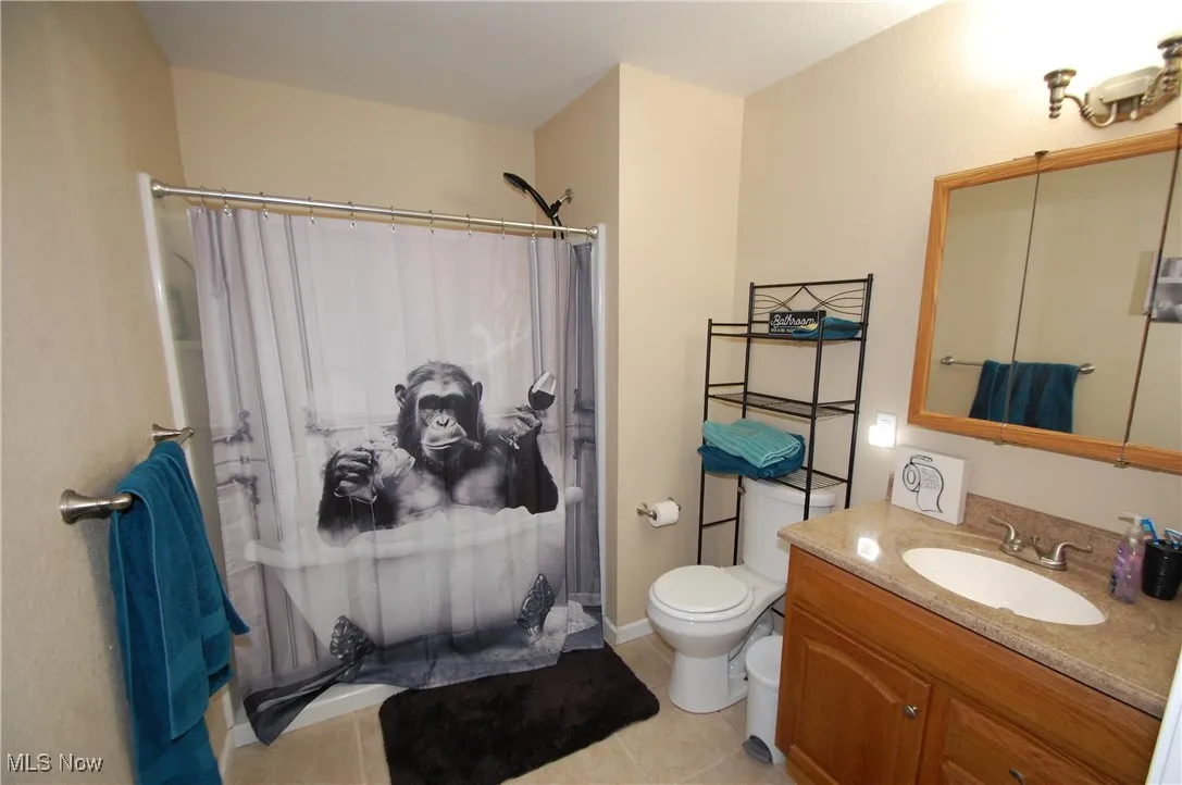 Bathroom featuring curtained shower, vanity, and light tile patterned flooring