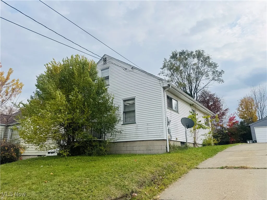 View of property exterior featuring a lawn, an outbuilding, and a detached garage