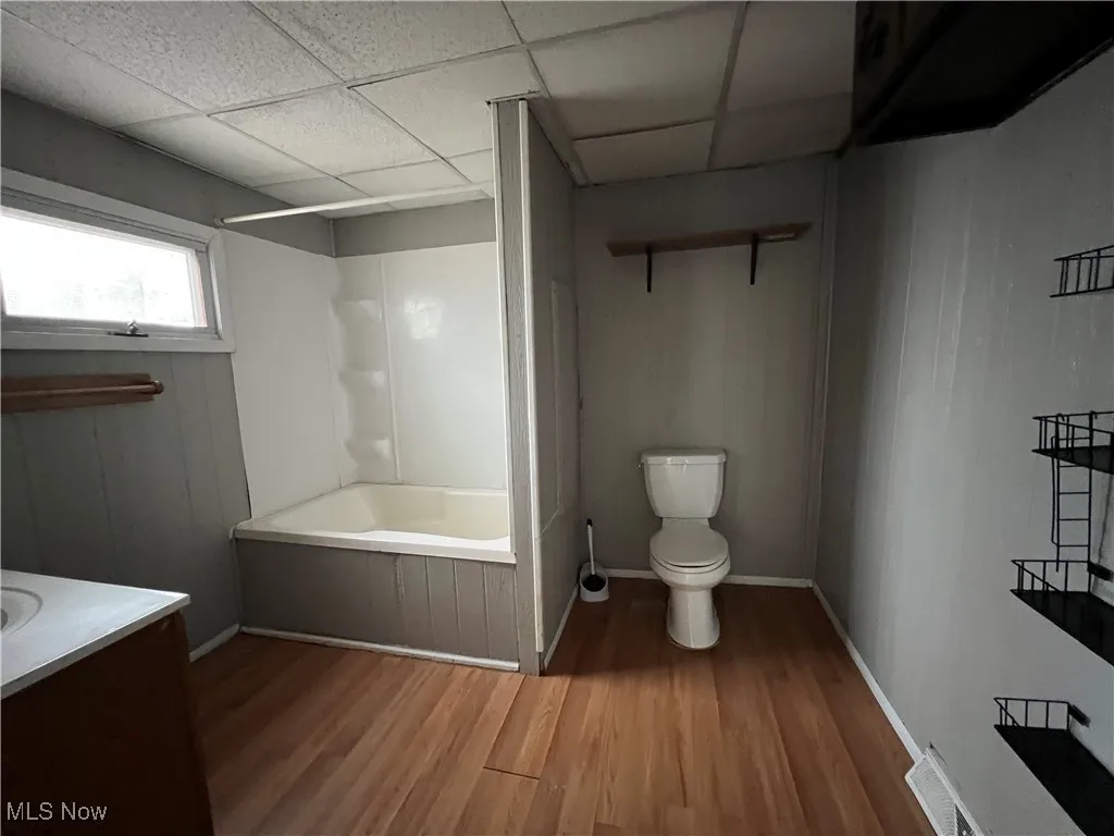 Bathroom with vanity, wood finished floors, a drop ceiling, and shower / washtub combination