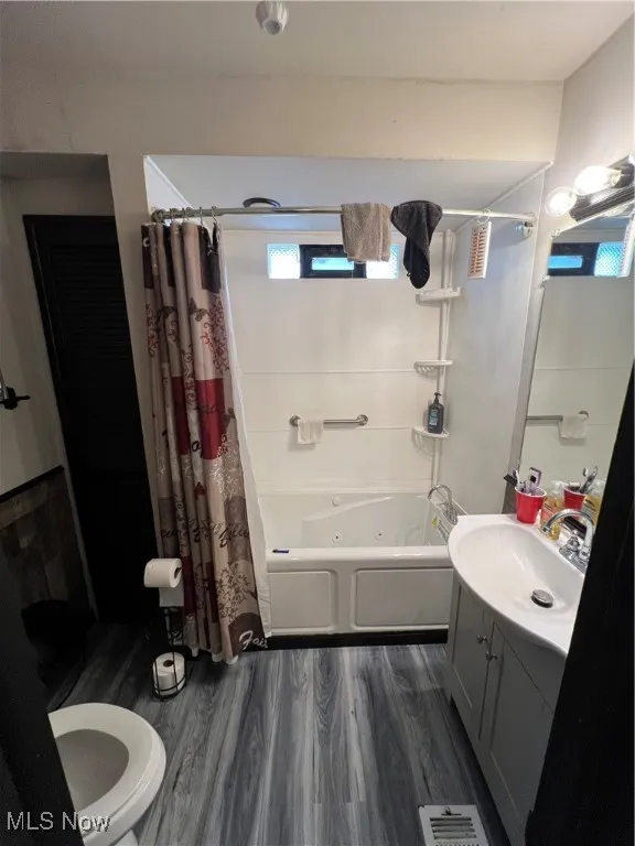 Full bath featuring vanity, dark wood-style floors, and a combined bath / shower with jetted tub